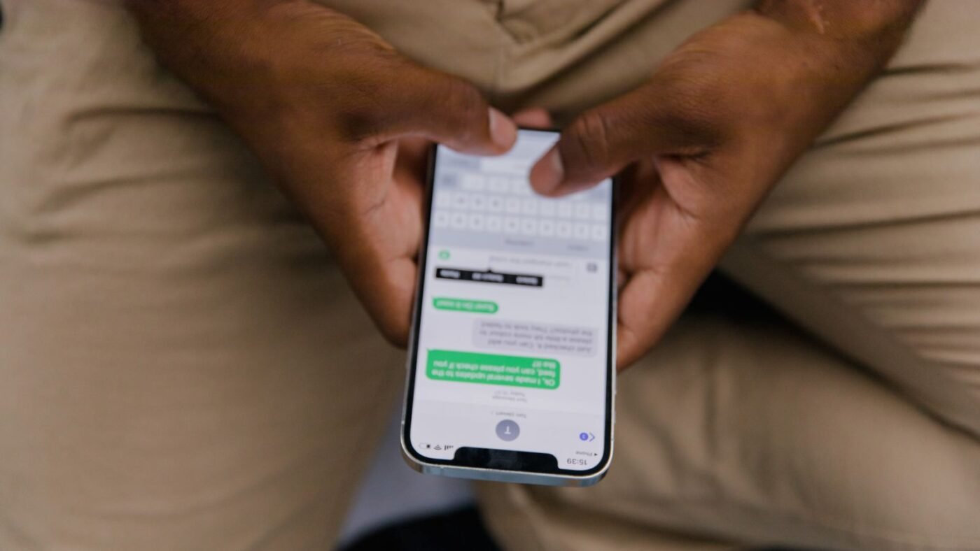 Mãos segurando um celular com uma conversa de mensagens aberta na tela