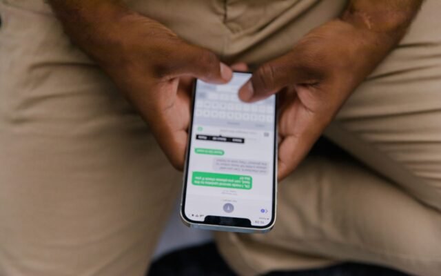 Mãos segurando um celular com uma conversa de mensagens aberta na tela