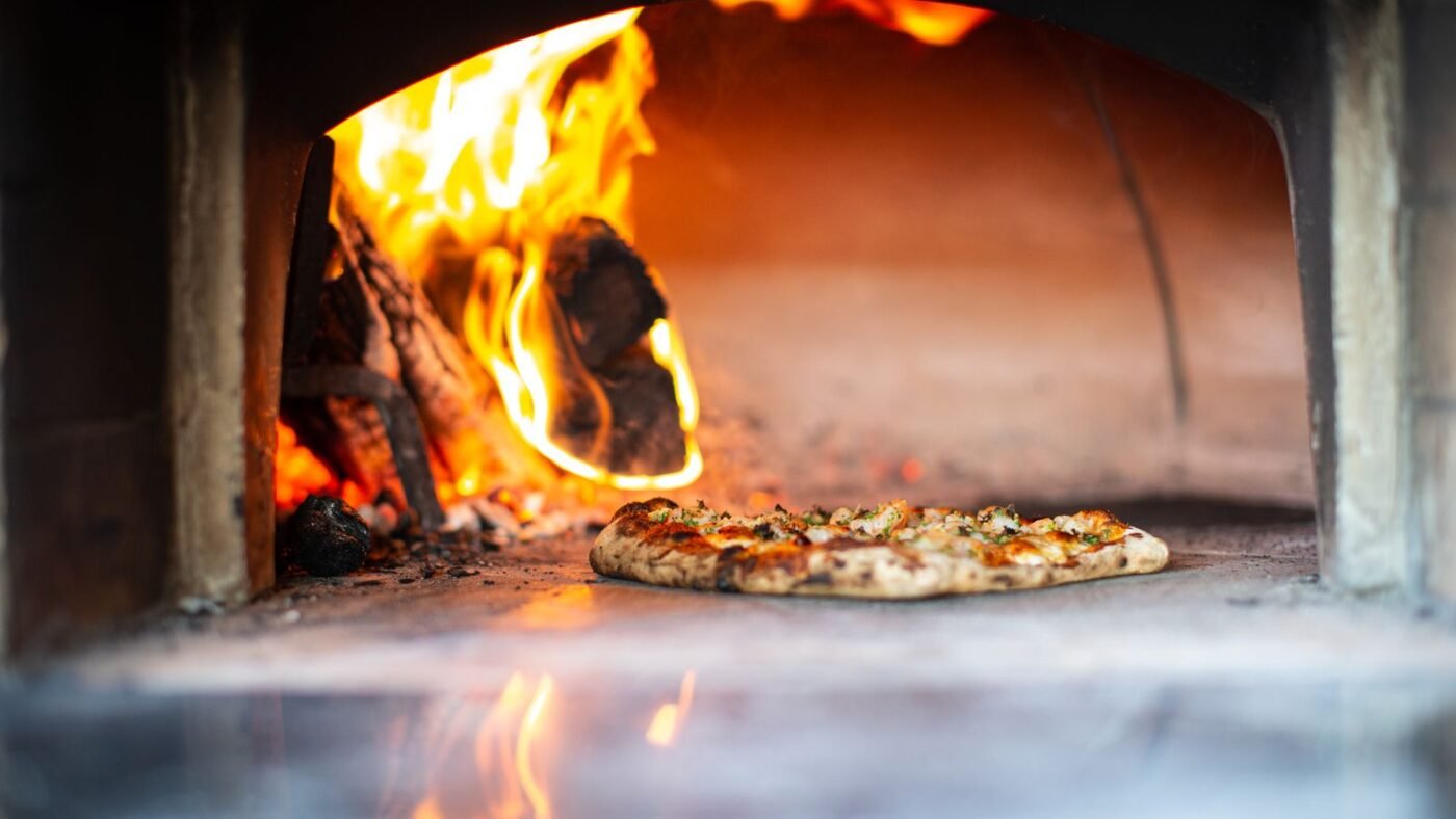 Pizza assando em forno a lenha