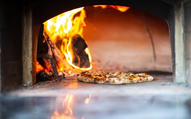 Pizza assando em forno a lenha