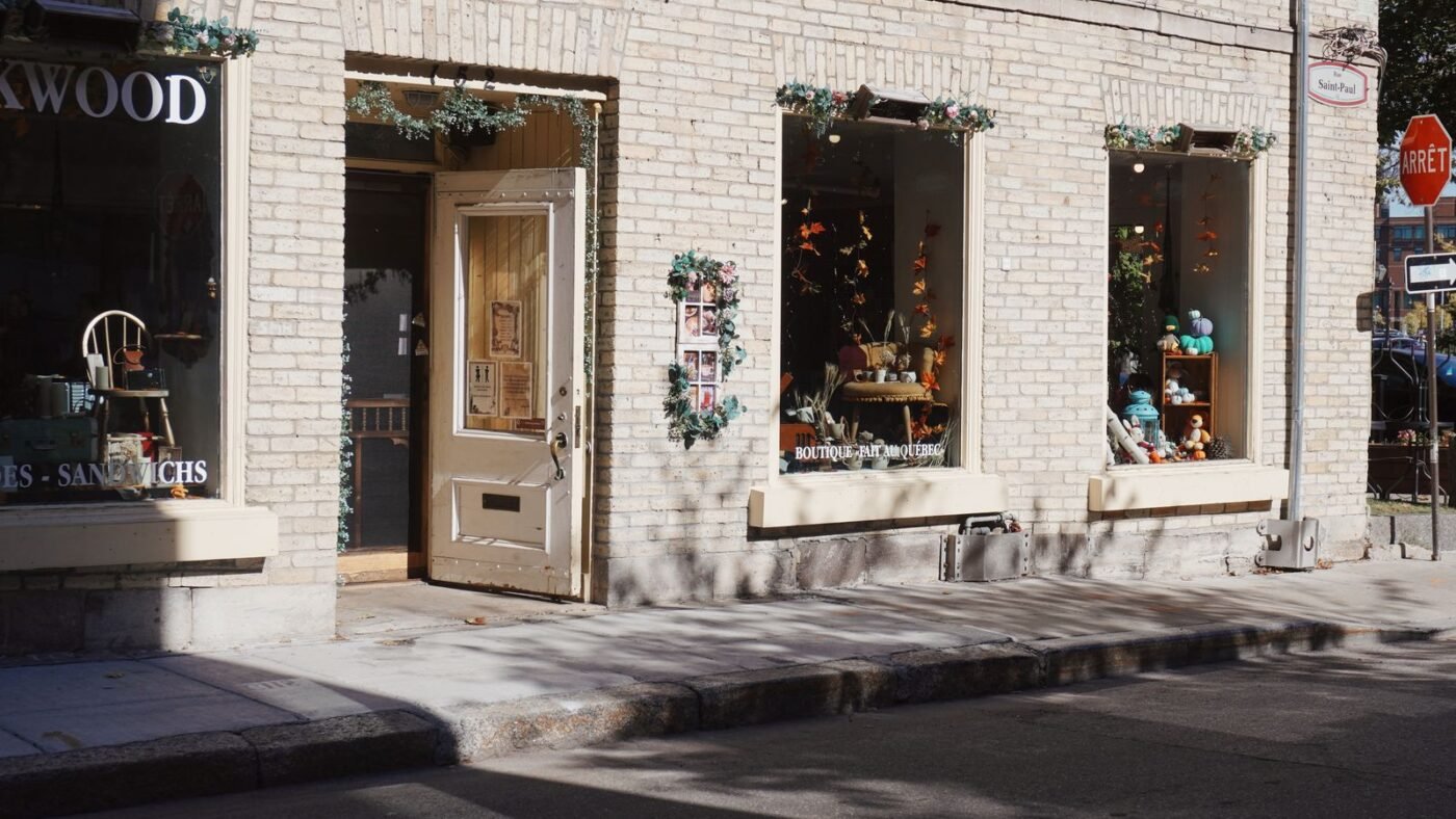 Fachada de loja de rua com vitrines decoradas, porta aberta e calçada em frente