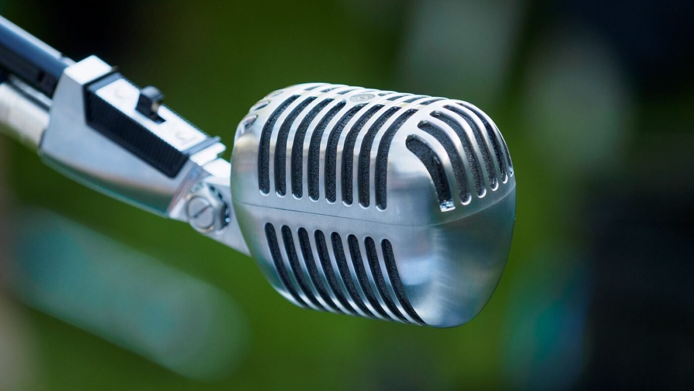 Microfone antigo de rádio, cromado, em close sobre fundo desfocado