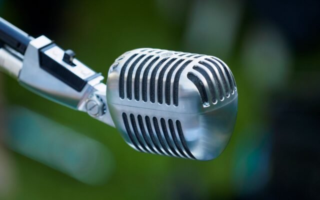 Microfone antigo de rádio, cromado, em close sobre fundo desfocado
